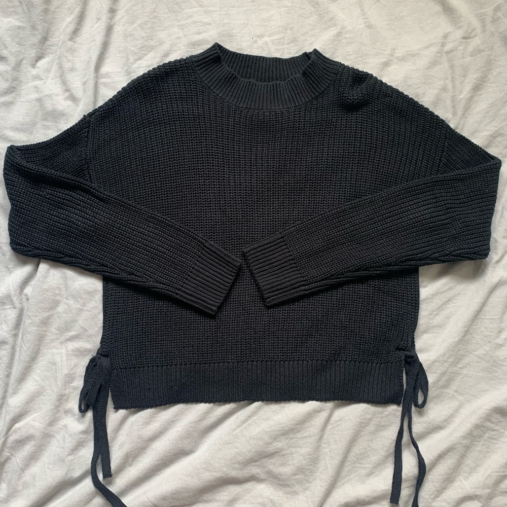 Black knit sweater with slits on the side. Slits tie at the bottom of sides.